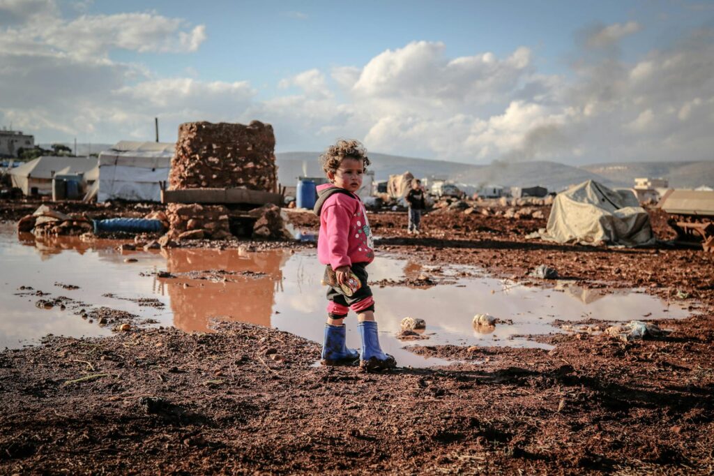 kid in sweatshirt standing on mud